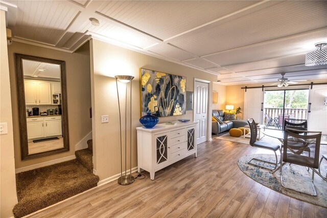 interior space featuring a barn door, hardwood / wood-style flooring, ceiling fan, and crown molding