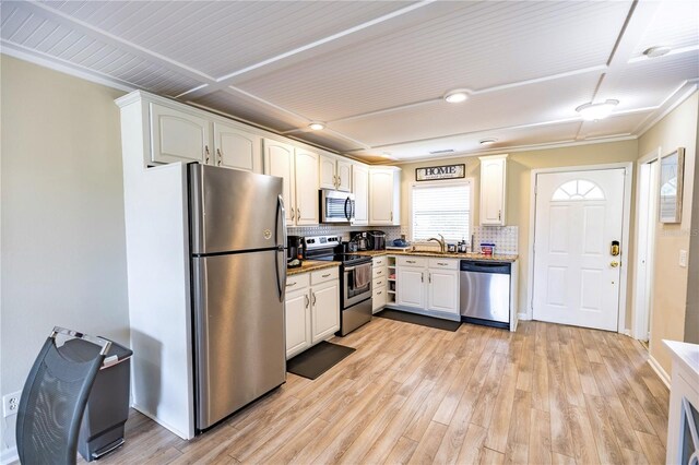 kitchen with appliances with stainless steel finishes, tasteful backsplash, sink, light hardwood / wood-style floors, and white cabinetry