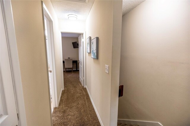 hallway with dark colored carpet and a textured ceiling