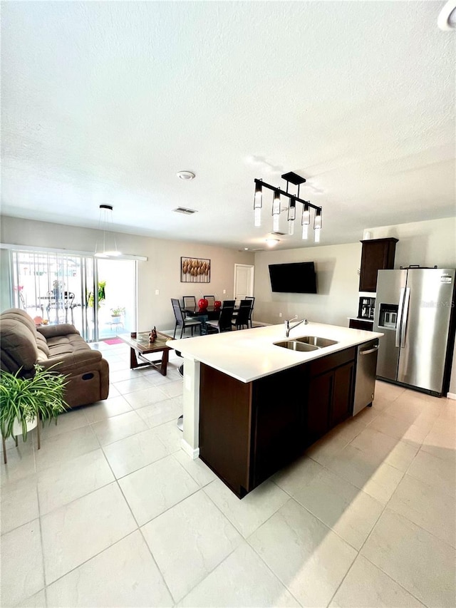 kitchen with appliances with stainless steel finishes, sink, a center island with sink, and dark brown cabinetry