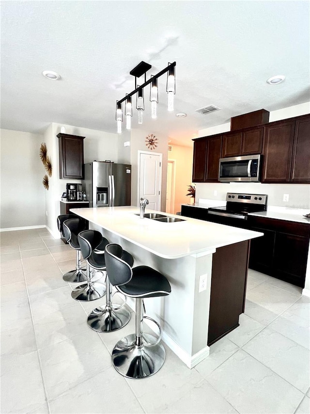 kitchen with sink, a kitchen breakfast bar, stainless steel appliances, and an island with sink