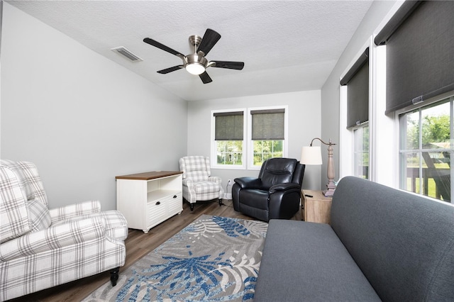 living area with ceiling fan, dark hardwood / wood-style floors, and a textured ceiling