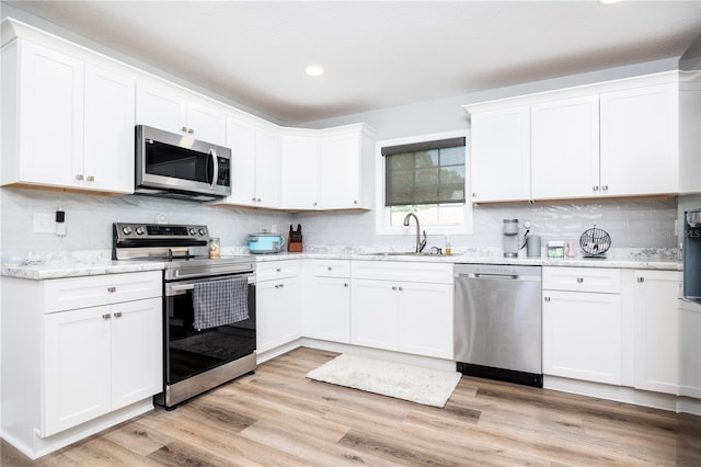 kitchen with white cabinetry, appliances with stainless steel finishes, sink, and light hardwood / wood-style flooring