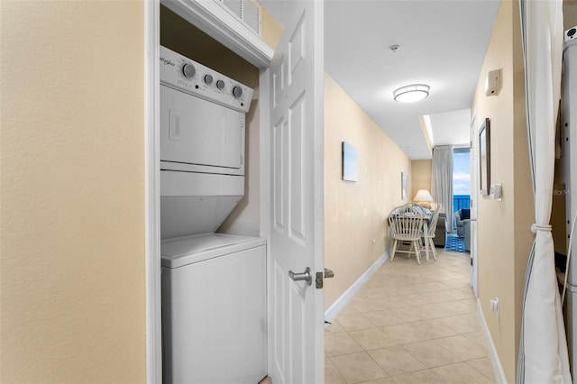 laundry area featuring stacked washing maching and dryer and light tile patterned floors