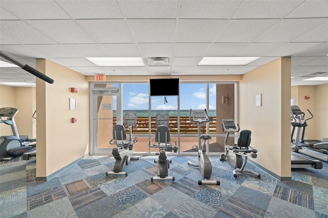 gym with a drop ceiling and carpet