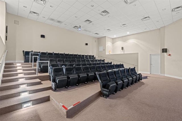 cinema with carpet flooring, a high ceiling, and a drop ceiling