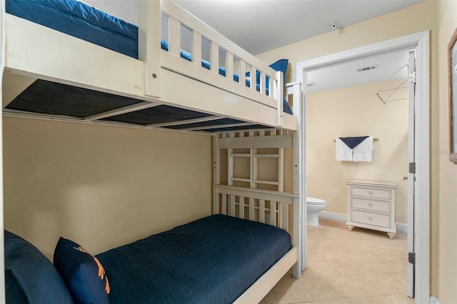 bedroom featuring baseboards, visible vents, connected bathroom, and light tile patterned flooring