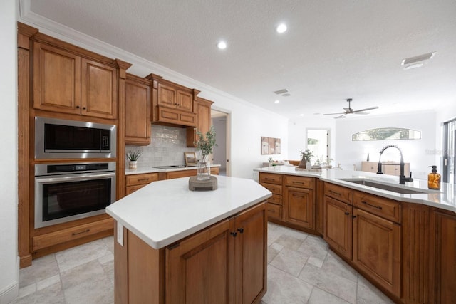 kitchen featuring appliances with stainless steel finishes, a textured ceiling, crown molding, sink, and a center island