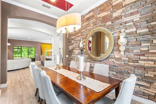 dining space featuring light hardwood / wood-style flooring, a notable chandelier, and ornamental molding