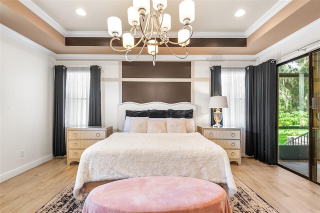 bedroom with hardwood / wood-style flooring, access to exterior, ornamental molding, a tray ceiling, and a chandelier