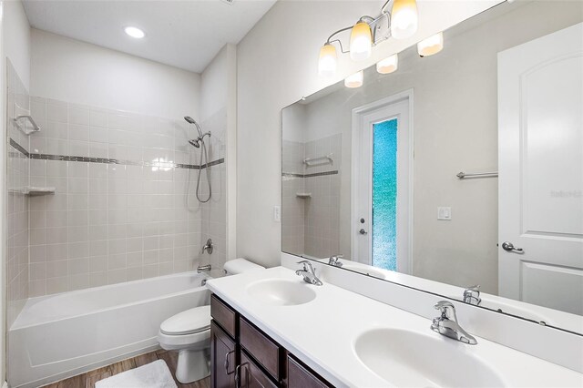 full bathroom with hardwood / wood-style flooring, vanity, toilet, and tiled shower / bath