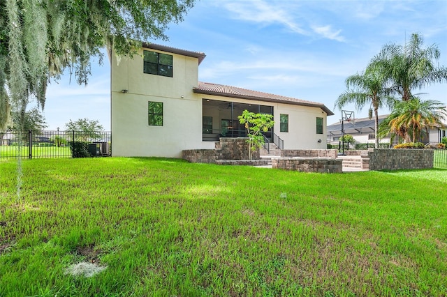 back of property featuring central AC unit, ceiling fan, and a lawn