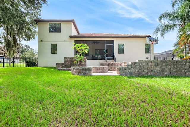 rear view of house with ceiling fan and a yard