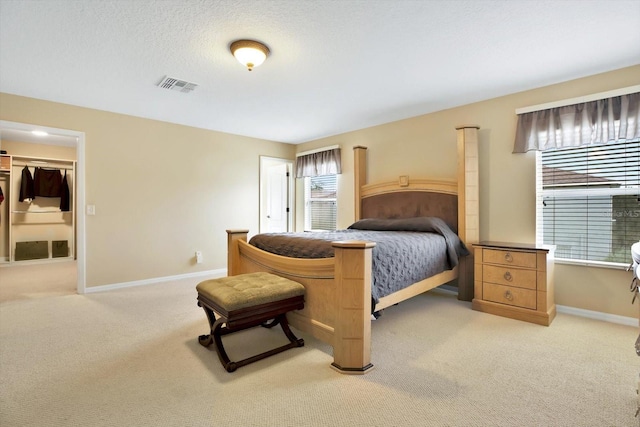 bedroom featuring light colored carpet, a walk in closet, and multiple windows