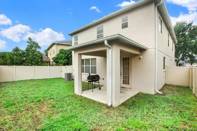 back of house featuring central AC unit, a patio area, and a lawn