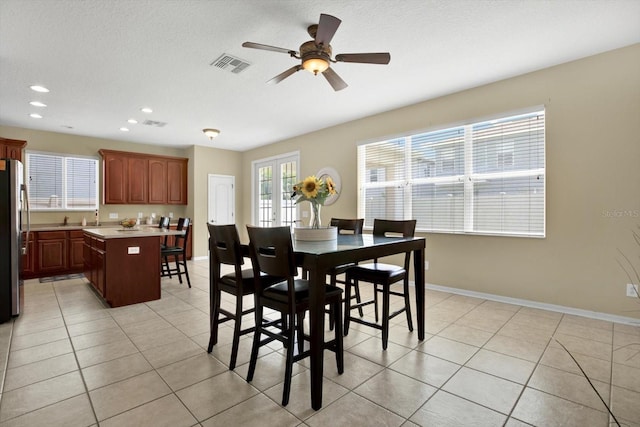 tiled dining room featuring ceiling fan, a textured ceiling, and french doors