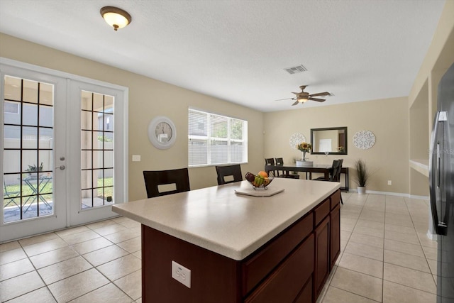 kitchen with ceiling fan, light tile patterned flooring, french doors, and a kitchen island