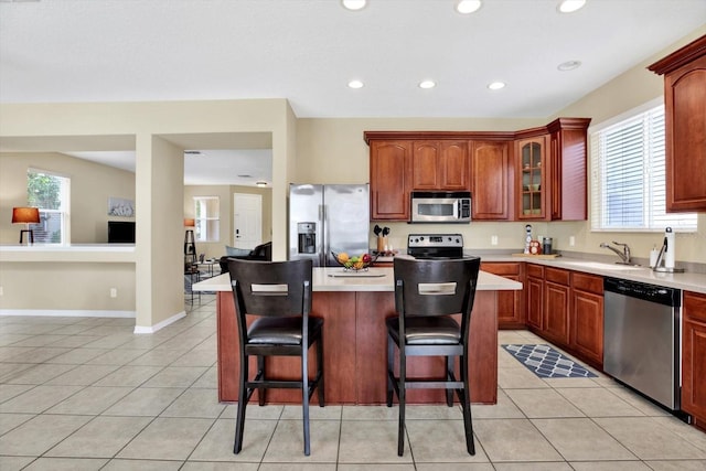 kitchen featuring light tile patterned floors, stainless steel appliances, plenty of natural light, and a center island