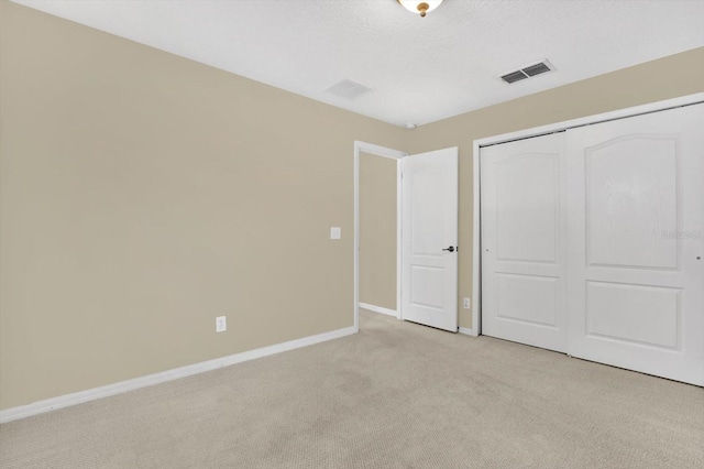 unfurnished bedroom featuring light carpet and a closet