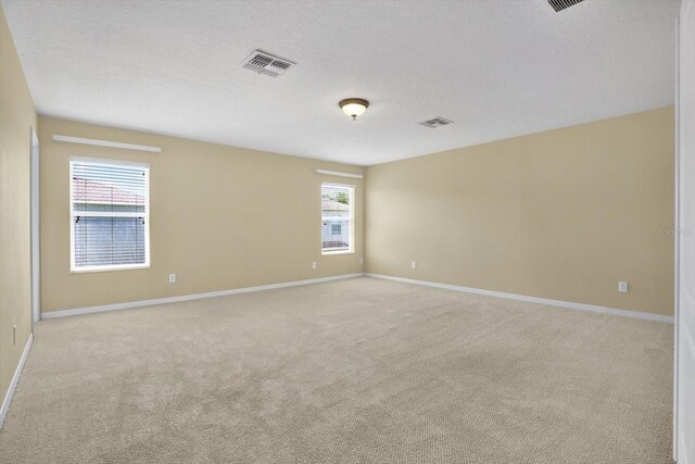 carpeted empty room with a textured ceiling