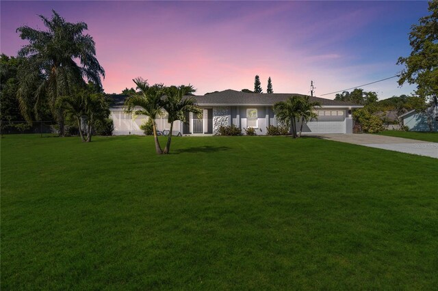 ranch-style house with a garage and a yard