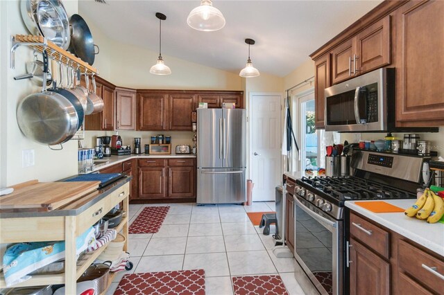 kitchen with decorative light fixtures, light tile patterned flooring, stainless steel appliances, and vaulted ceiling