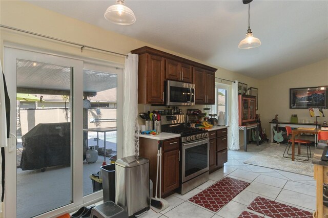 kitchen with a wealth of natural light, decorative light fixtures, appliances with stainless steel finishes, and vaulted ceiling