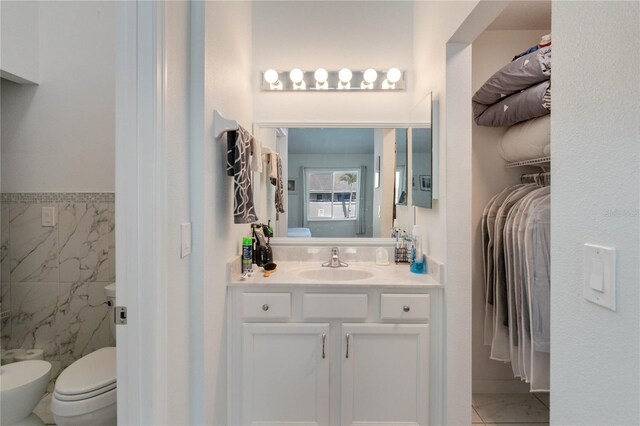 bathroom featuring tile patterned floors, vanity, toilet, and tile walls