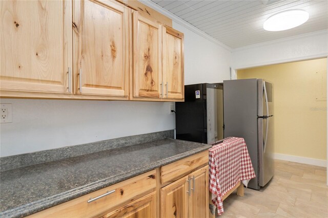 kitchen with light brown cabinets, ornamental molding, stainless steel refrigerator, and dark stone counters