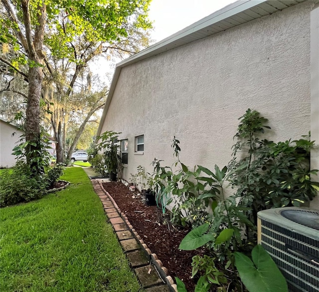 35226 Janine Dr, Zephyrhills, FL 33541 - view of side of home with stucco siding, central air condition unit, and a lawn