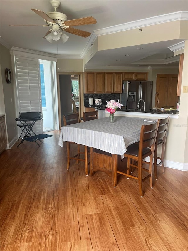 dining room featuring light hardwood / wood-style floors, ornamental molding, and ceiling fan