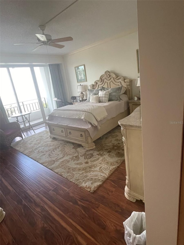 bedroom featuring a textured ceiling, dark hardwood / wood-style flooring, access to exterior, ceiling fan, and crown molding