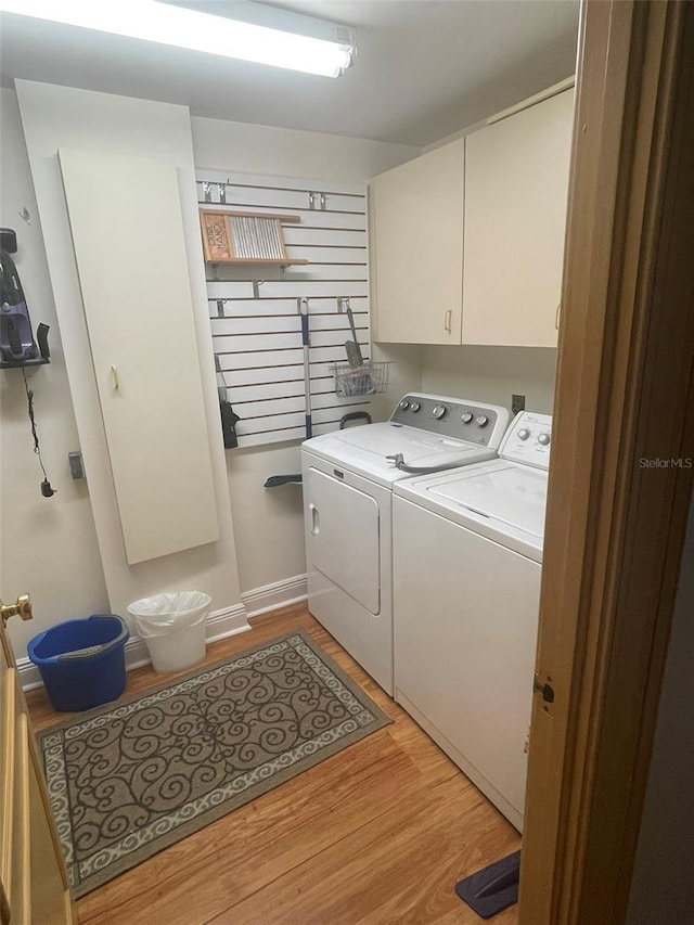 laundry area featuring separate washer and dryer, light hardwood / wood-style flooring, and cabinets