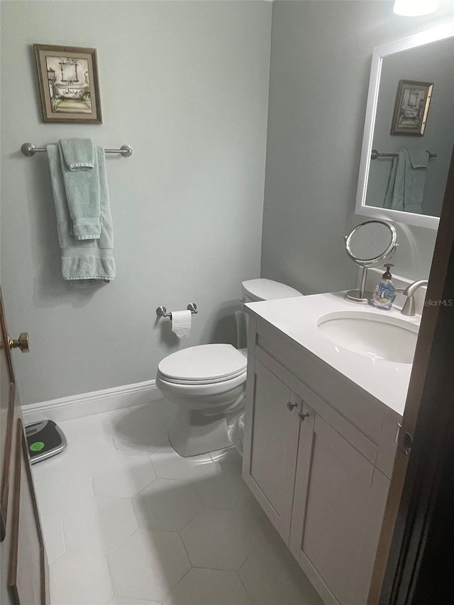 bathroom with toilet, vanity, and tile patterned flooring