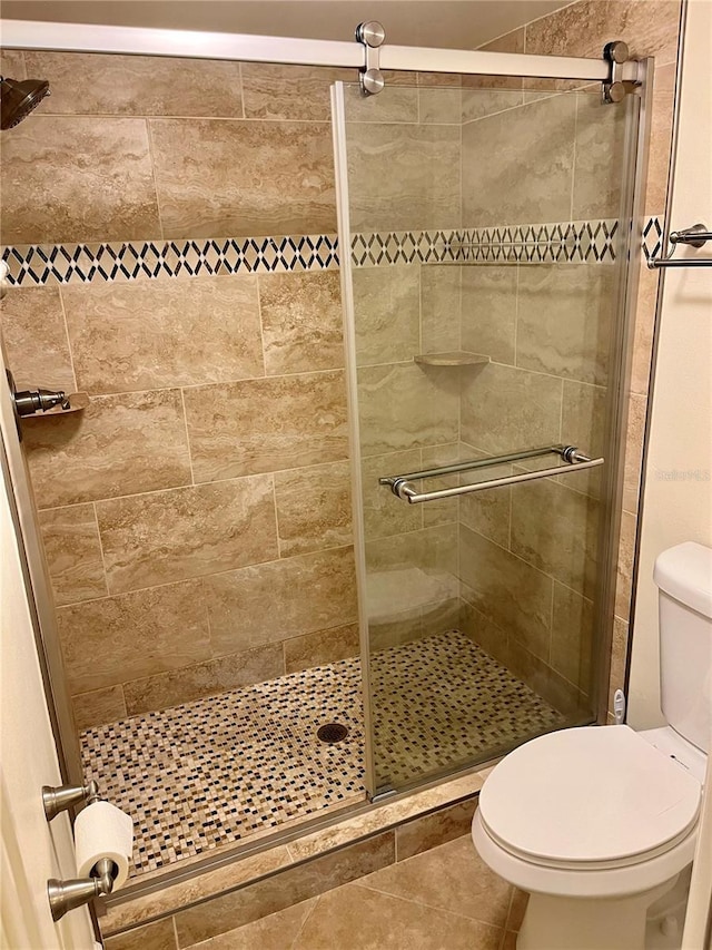 bathroom with toilet, an enclosed shower, and tile patterned flooring