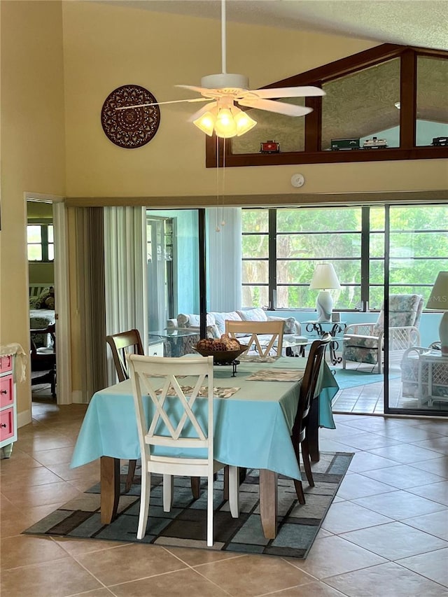 tiled dining area with ceiling fan, a wealth of natural light, and a high ceiling