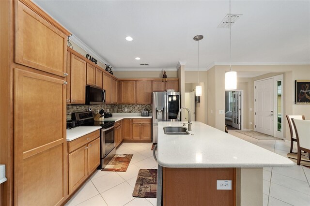 kitchen featuring backsplash, a kitchen island with sink, hanging light fixtures, sink, and stainless steel appliances