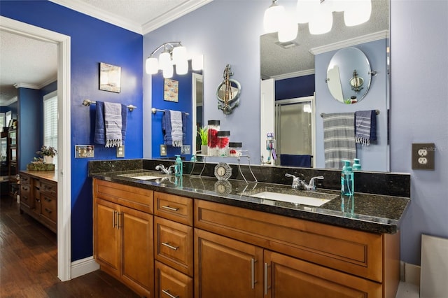 bathroom featuring vanity, wood-type flooring, ornamental molding, and a textured ceiling