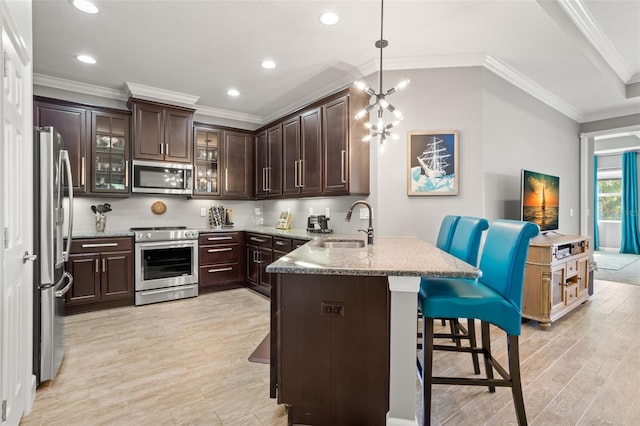 kitchen with pendant lighting, dark brown cabinets, a kitchen bar, and appliances with stainless steel finishes