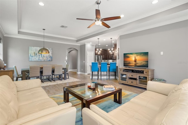 living room with ceiling fan, crown molding, and light hardwood / wood-style flooring