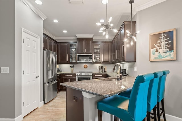 kitchen with dark brown cabinetry, sink, hanging light fixtures, an inviting chandelier, and appliances with stainless steel finishes