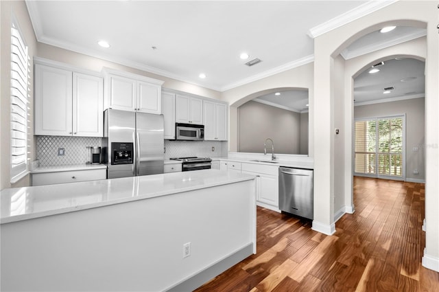 kitchen featuring decorative backsplash, hardwood / wood-style flooring, appliances with stainless steel finishes, and ornamental molding