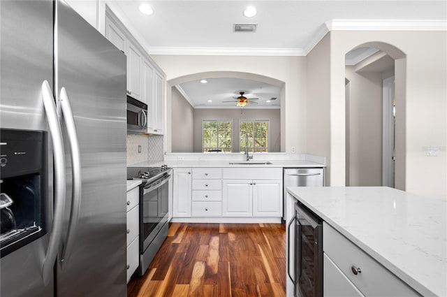 kitchen featuring ornamental molding, dark wood-type flooring, beverage cooler, and stainless steel appliances