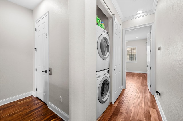 washroom with stacked washer and dryer, crown molding, dark hardwood / wood-style flooring, and a barn door