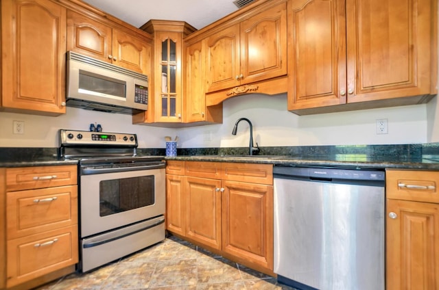 kitchen featuring dark stone countertops, sink, and stainless steel appliances