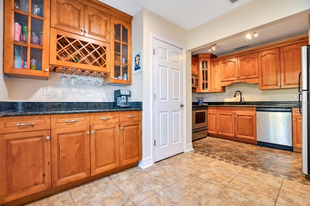 kitchen with dark stone countertops, sink, and appliances with stainless steel finishes