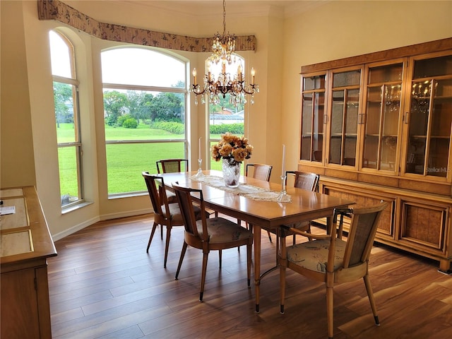 dining area featuring dark wood-type flooring, a chandelier, and ornamental molding