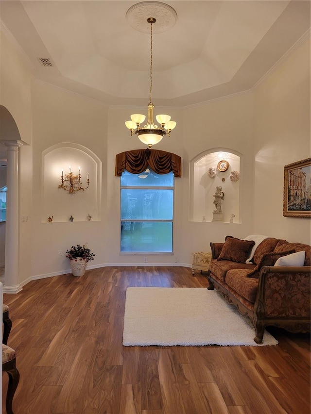 living room with ornate columns, wood-type flooring, a raised ceiling, and a notable chandelier