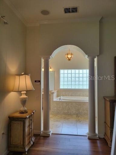 hall featuring dark wood-type flooring, a notable chandelier, ornamental molding, and decorative columns