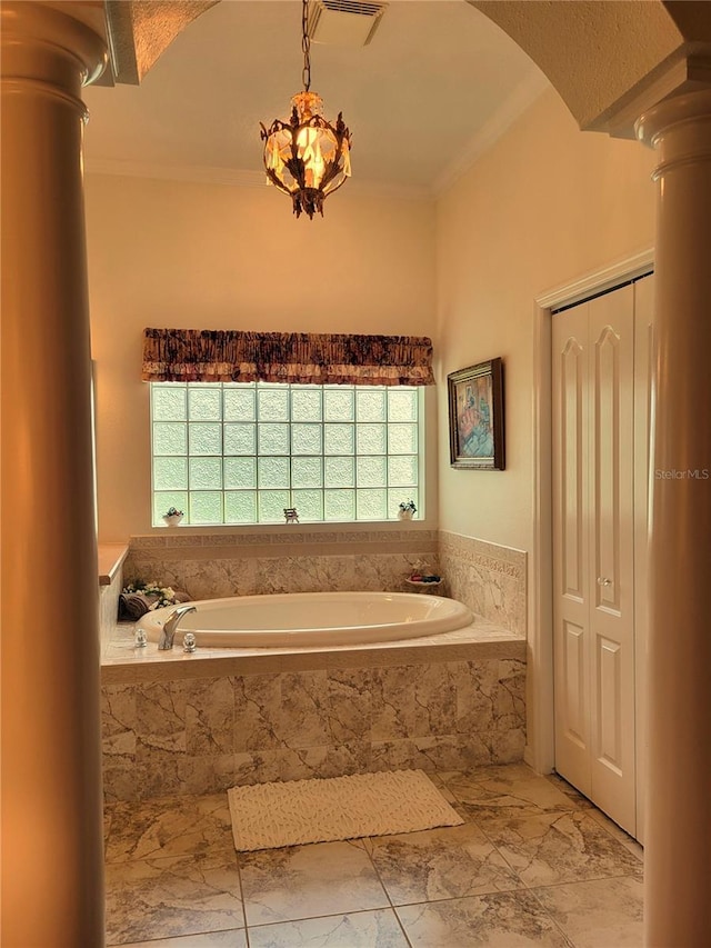 bathroom with ornamental molding, a relaxing tiled tub, and decorative columns